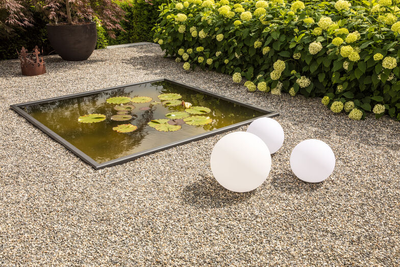 Die Gartenleuchten setzen den kleinen Seerosenteich in Szene.
