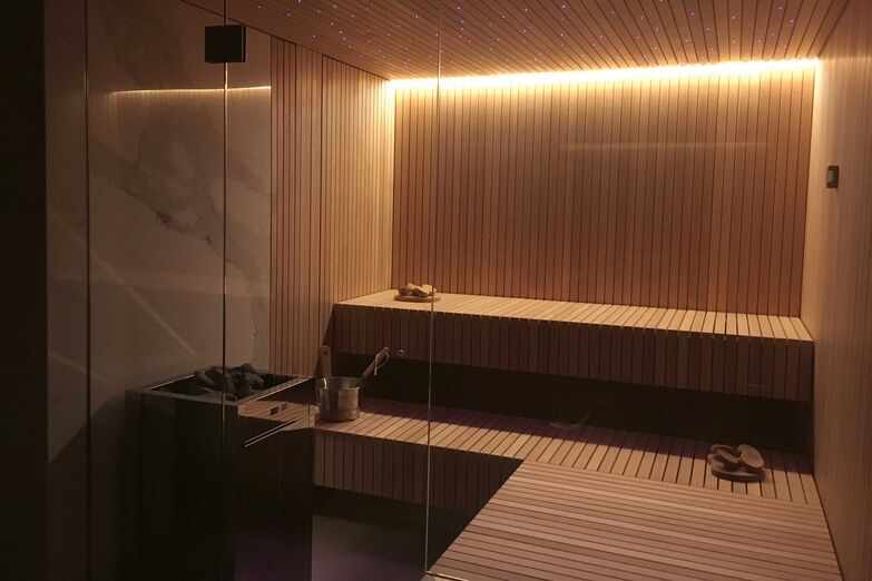 Das Interieur ist in Hemlock-Holz gefertigt. Beheizt wird mit einem Biosauna-Ofen in Edelstahl. In der Steinwand sind die Wellness-Steuerung, ein Audio-System, eine indirekte, dimmbare LED-Beleuchtung sowie ein Sternenhimmel angebracht. Ging Saunabau AG, www.saunabau.ch